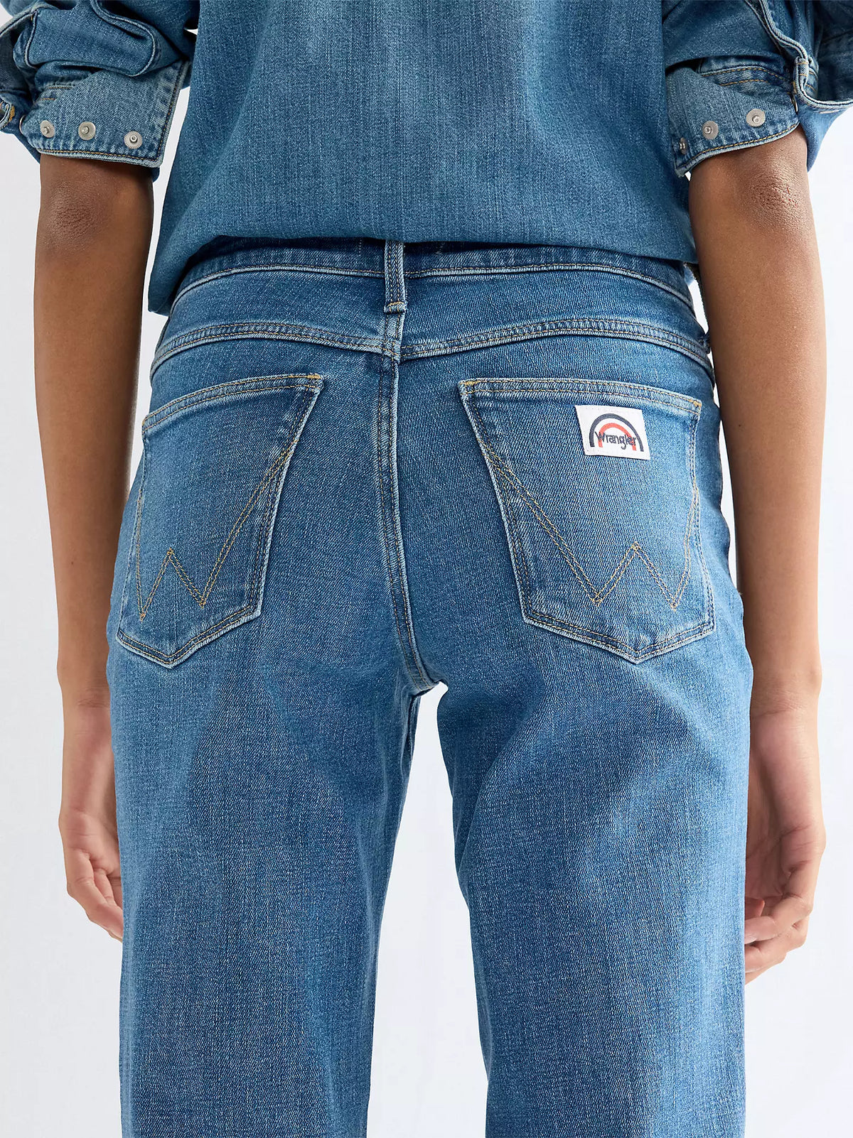 Wrangler Flare Indigo Rush bukser med høyt liv og klassisk denimfarge, vises med brede ben og forsterkede sømmer.