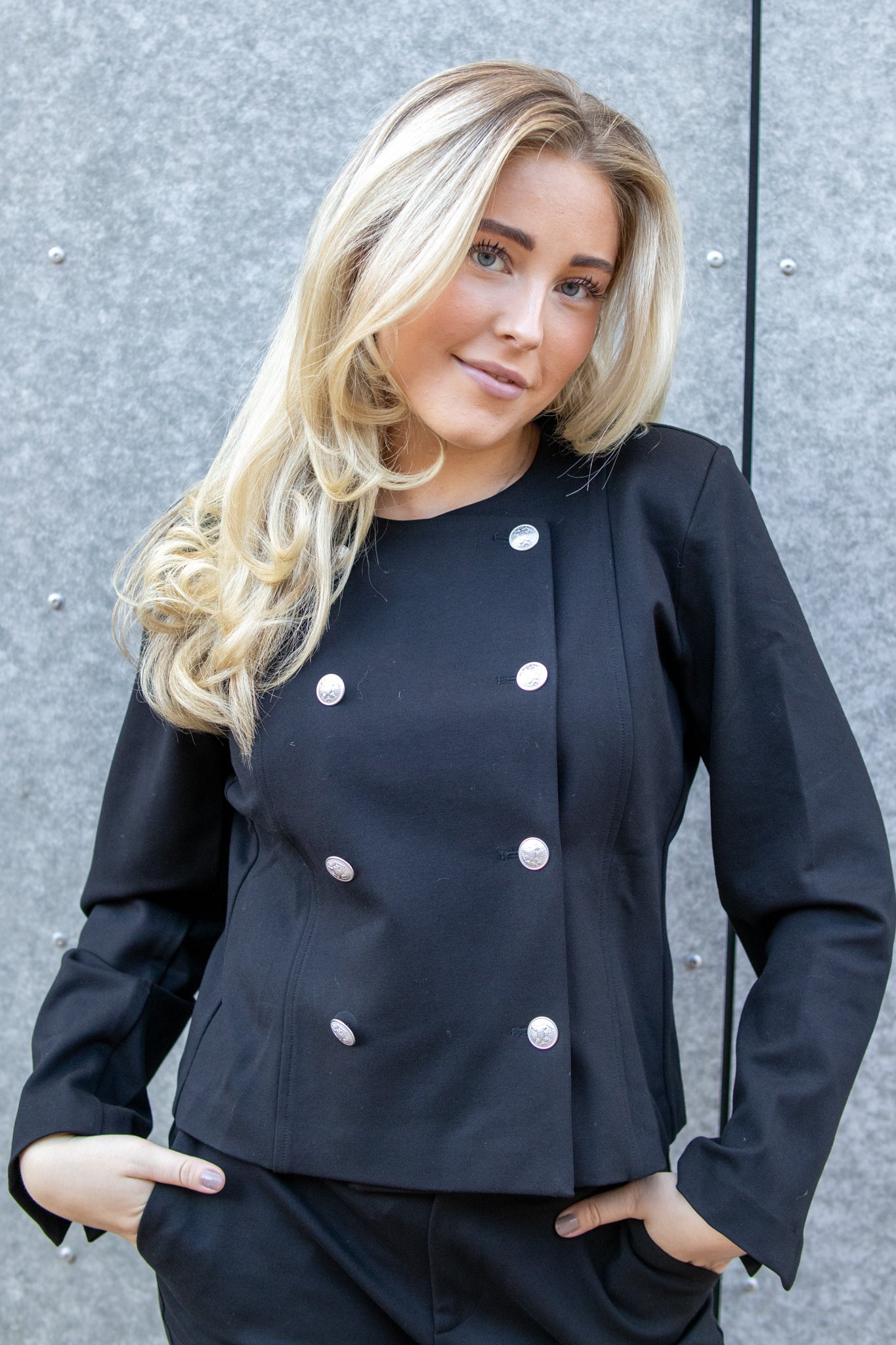 Sort Ella Button-jakke fra Pieszak, helthvit jakke med knapper, vist på en modell foran en nøytral bakgrunn.
